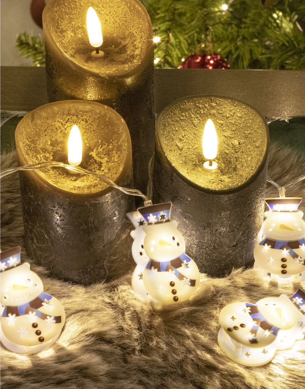 led sneeuwpopslinger liggend tussen 3 kaarsen